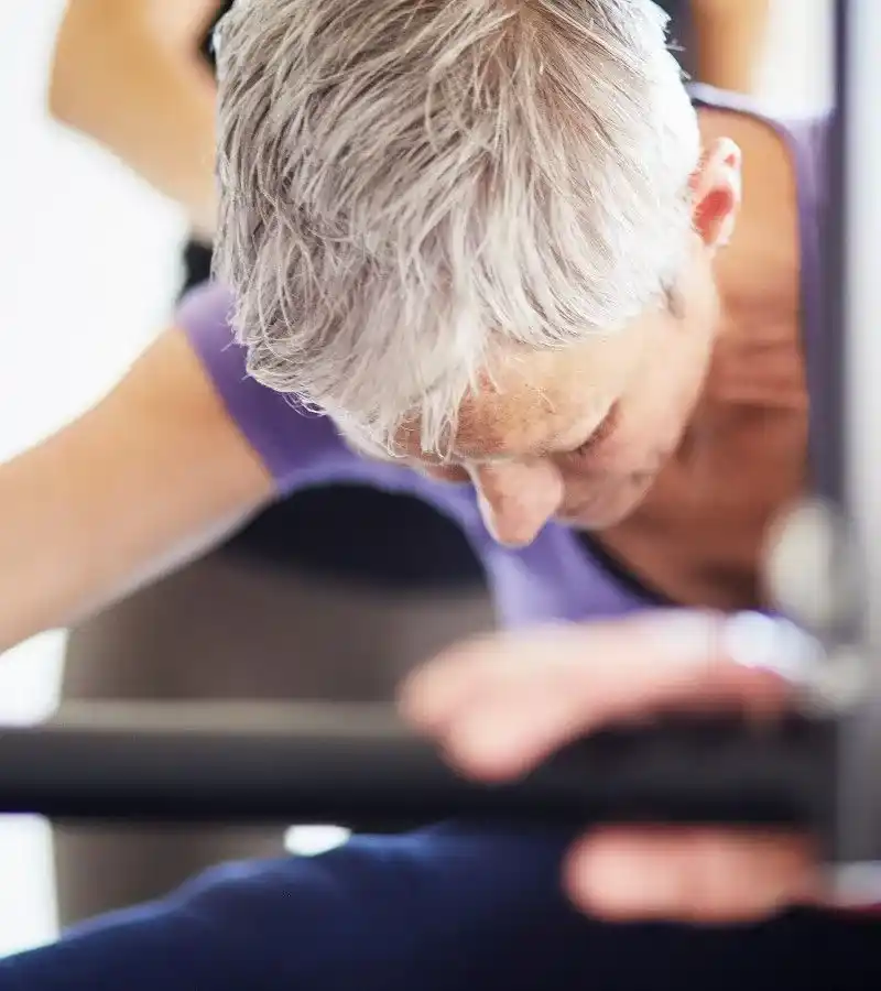 Una señora mayor haciendo en clase de pilates para rehabilitación de una lesión.