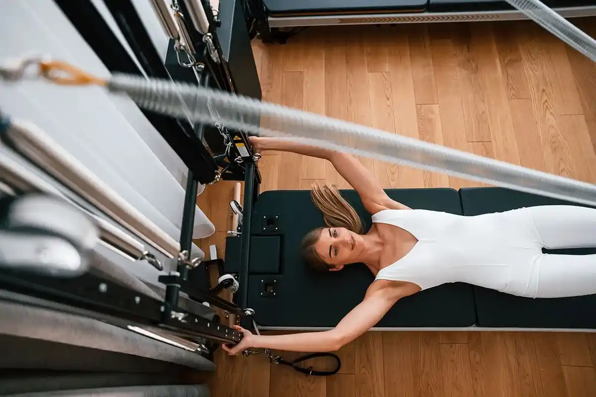 Vista desde arriba de una chica haciendo ejercicios de pilates en el reformer.
